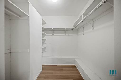 A long hallway with white walls and wooden floors.
