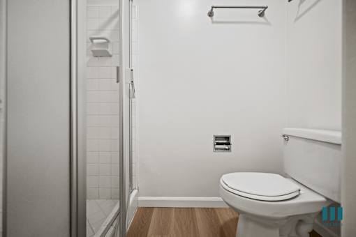 A white toilet in a small bathroom with a walk-in shower.