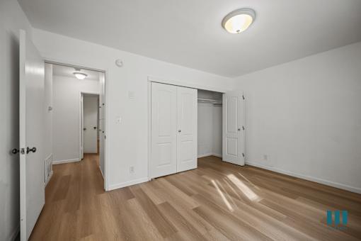 A room with white walls and wooden flooring with a light on the ceiling.