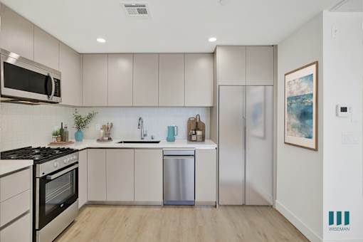 A kitchen with a stainless steel dishwasher and a fridge.