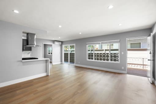 an empty living room with a kitchen and a large window