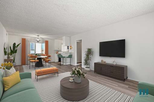 A living room with a green sofa, a wooden coffee table, and a flat-screen TV mounted on the wall.