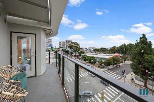 A balcony with a chair and a view of a city street.