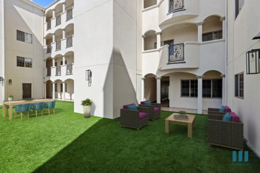 a courtyard with a lawn and chairs in front of a building