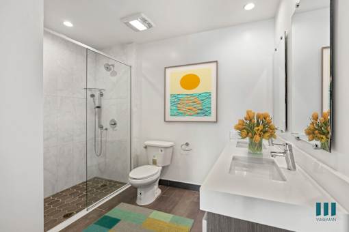 A bathroom with a white toilet, a white sink, and a shower with a glass door.