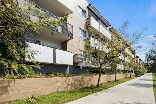 A modern apartment building with balconies and a sidewalk.