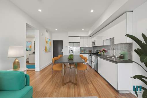 A modern kitchen with a green couch and a wooden table.