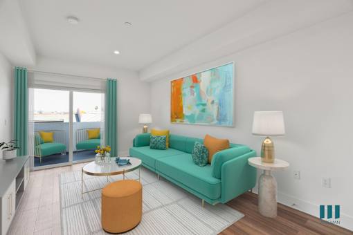 A living room with a green couch and a painting on the wall.