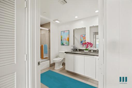 A bathroom with a toilet, sink, and mirror.