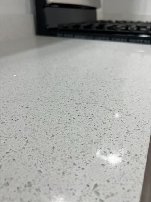 a close up of a white counter top with a stove in the background