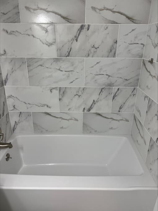a bathtub in a bathroom with a tiled wall and floor