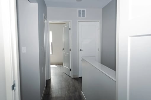 A hallway with white doors and a white wall.