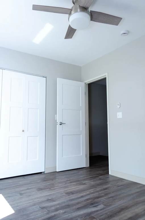 A room with a ceiling fan and two doors.