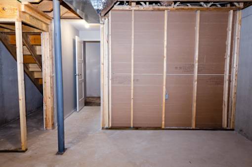 A room under construction with wooden framing and a staircase on the left.