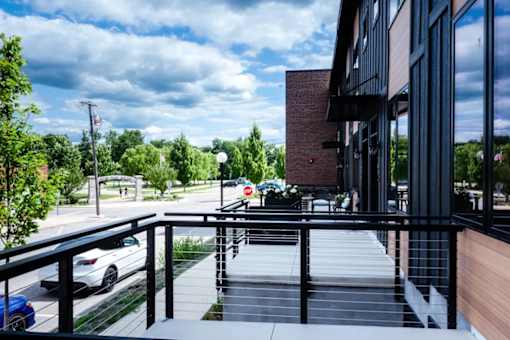 A balcony with a railing overlooks a parking lot and trees.