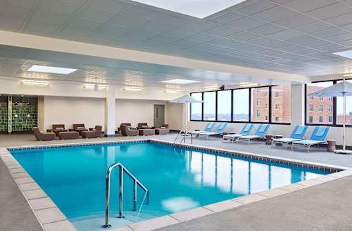 A large indoor swimming pool with lounge chairs and a glass wall.