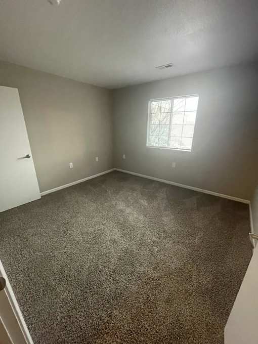 A room with a carpeted floor and a window.