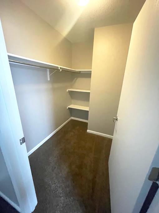 A small, empty room with a door on the left and a shelf on the right.