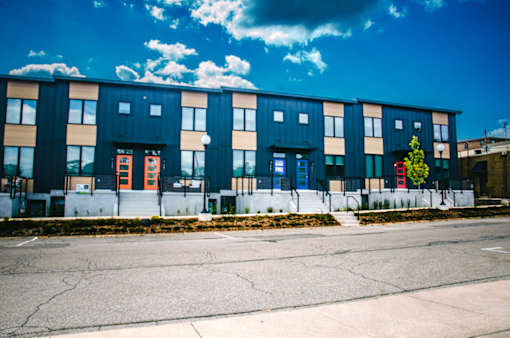 A row of modern townhouses with a clear blue sky above.
