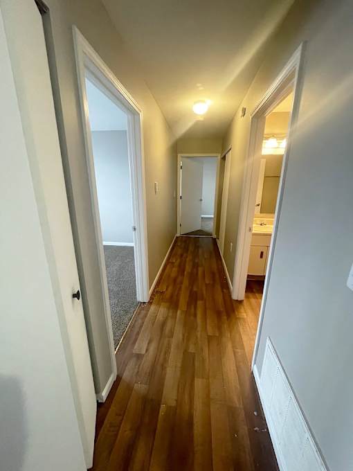 A long hallway with wood floors and white walls.