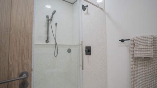 A shower area with a glass door and a towel hanging on the wall.