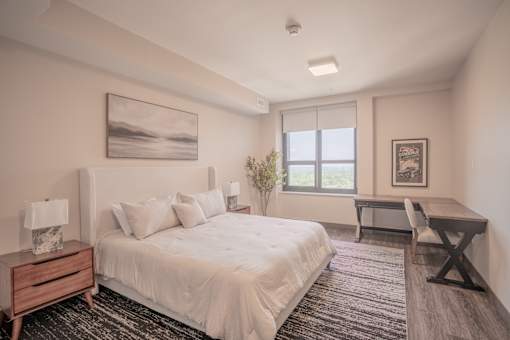 A bedroom with a large bed, a desk, and a chair.