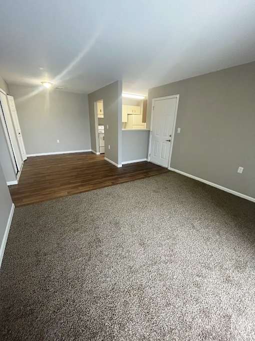 A room with a carpeted floor and a door on the right side.