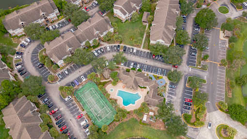 A bird's eye view of a residential area with a swimming pool and tennis court.