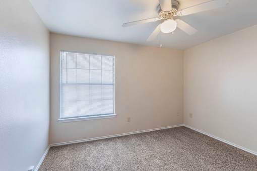 A room with a ceiling fan and carpeted floor.