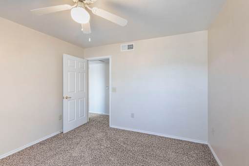A room with a ceiling fan and carpeted floor.