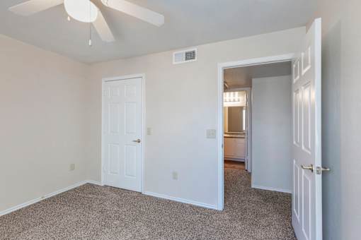 A room with a ceiling fan and two doors.