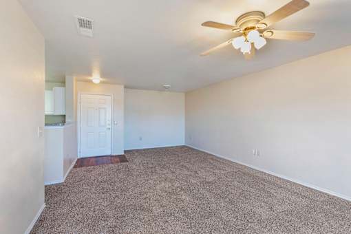 A room with a ceiling fan and carpeted floor.