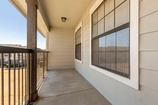 A balcony with a metal railing and a window with blinds.