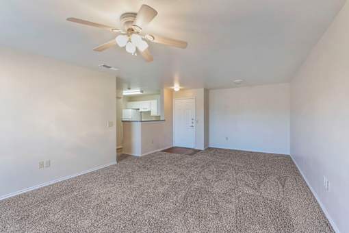 A room with a ceiling fan and carpeted floor.