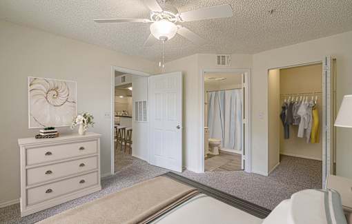 A white room with a dresser and a ceiling fan.