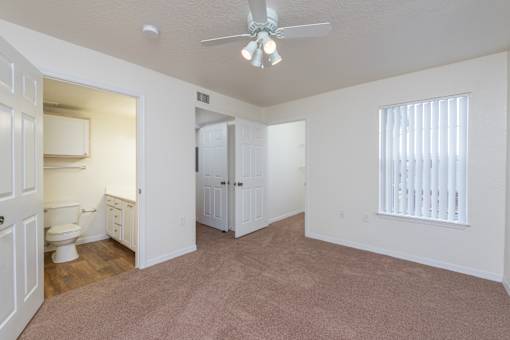 A room with a carpeted floor and a ceiling fan.