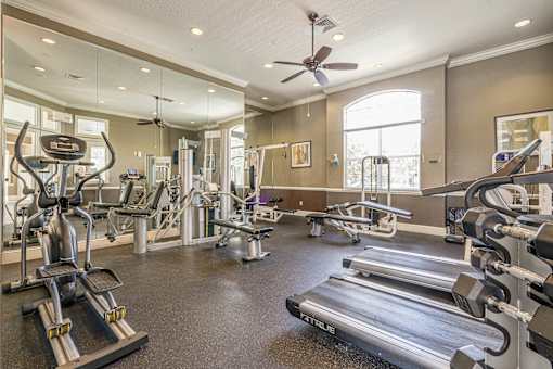 A spacious gym with a variety of equipment including treadmills, weights, and a bench.