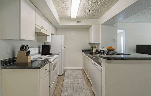 A kitchen with white cabinets and black countertops.
