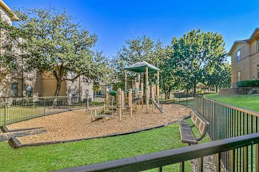 A playground with a swing set and a green gazebo.