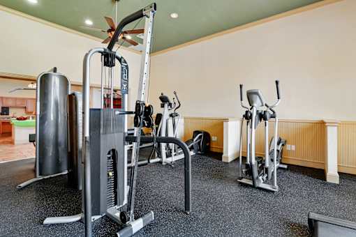 A gym with a variety of equipment including a treadmill, a stationary bike, and a weight machine.