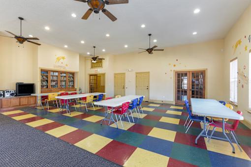 A room with tables and chairs and a ceiling fan.