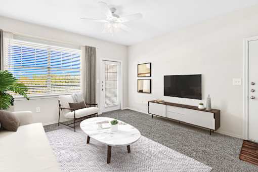 A living room with a white couch, a coffee table, a television, and a plant.