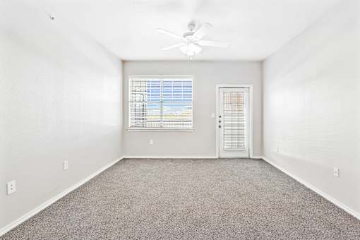 A room with a ceiling fan and a window with blinds.