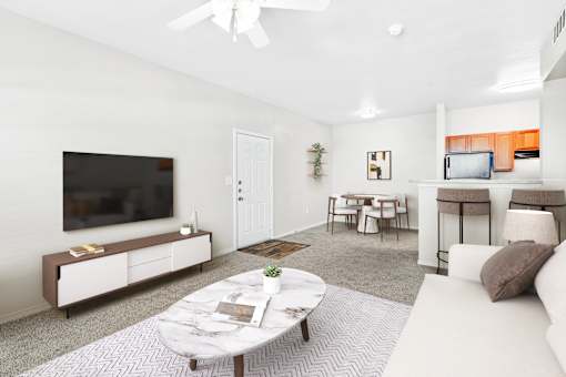 A living room with a white couch, a coffee table, and a flat screen TV.