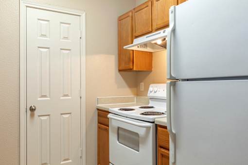 A white refrigerator stands in a kitchen next to a white door.