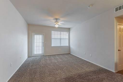 A room with a carpeted floor and a ceiling fan.