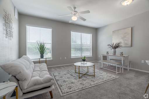 A living room with a white couch, a coffee table, and a ceiling fan.