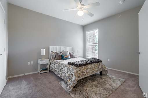 A bedroom with a bed, nightstand, and window.