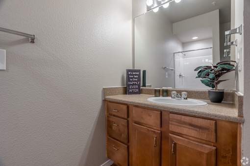 A bathroom with a sink, mirror, and wooden cabinets.