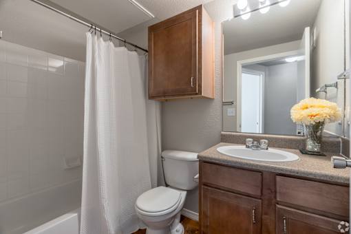 A white shower curtain hangs over a white bathtub in a bathroom.